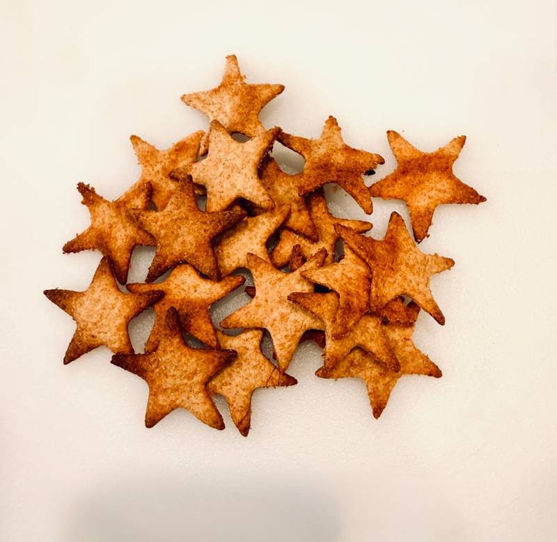 Golden crispy star crackers made from Einkorn fresh milled flour. Crackers are sitting on solid white cuttingboard
