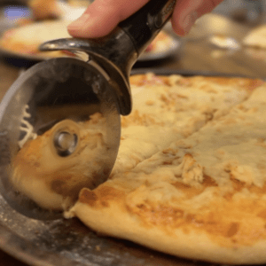 Pizza with pizza cutter and hand