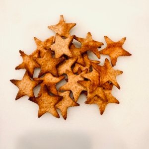 Golden crispy star crackers made from Einkorn fresh milled flour. Crackers are sitting on solid white cuttingboard