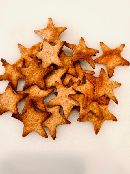 Golden crispy star crackers made from Einkorn fresh milled flour. Crackers are sitting on solid white cuttingboard