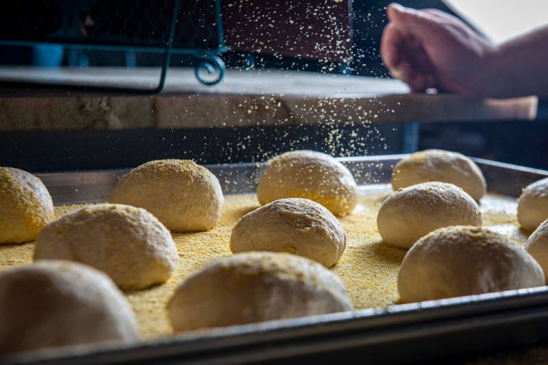 Close-up of dough balls in a bakery setting, ready for baking with a sprinkle of flour.